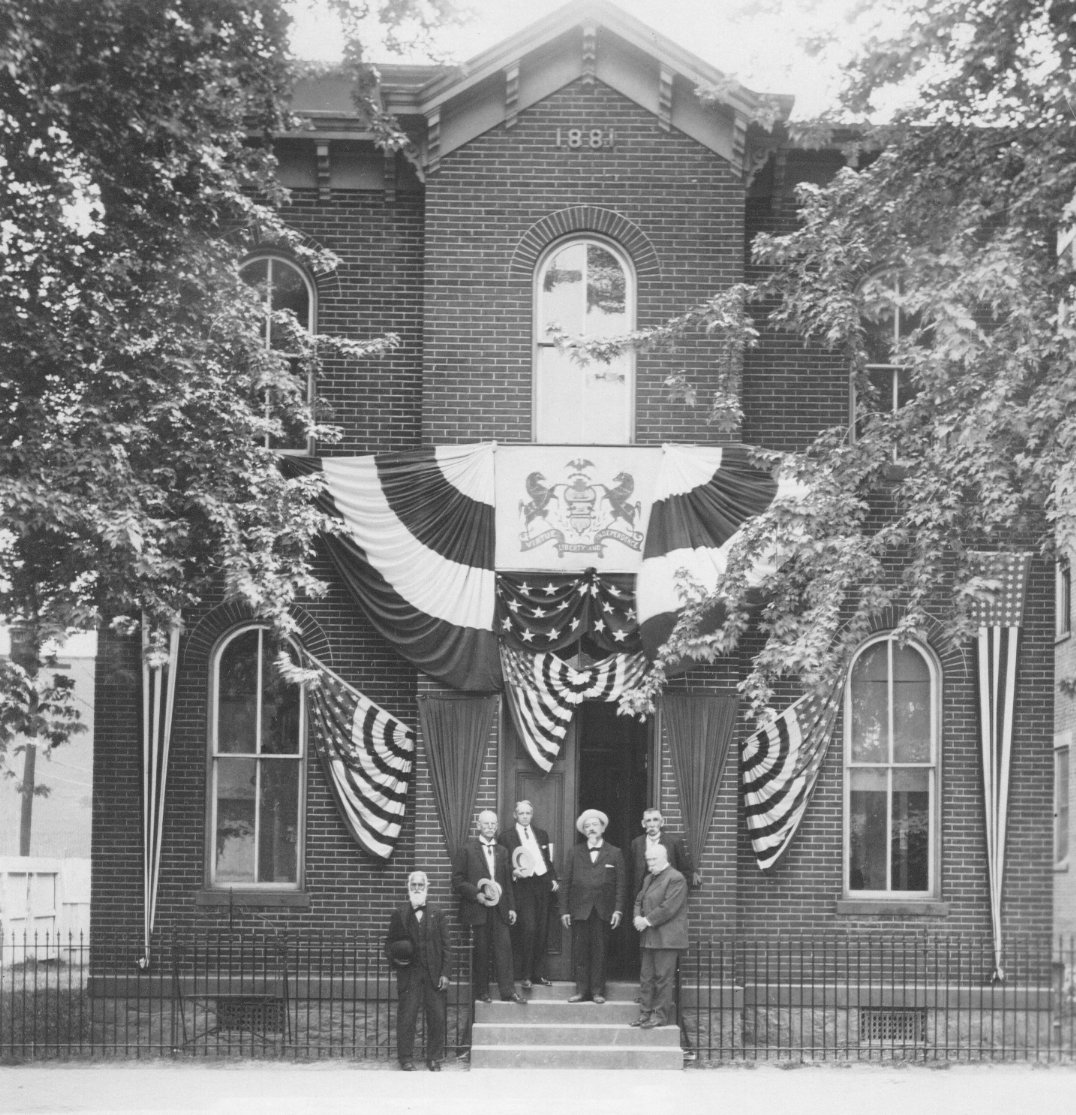 Photo of the Hamilton Library Building with group of men in front. Building decorated with bunting for the 1909 Old Home Week.