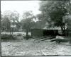 Huntsdale--this photo shows two wooden buildings with logs and bits of wood strewn on the ground.